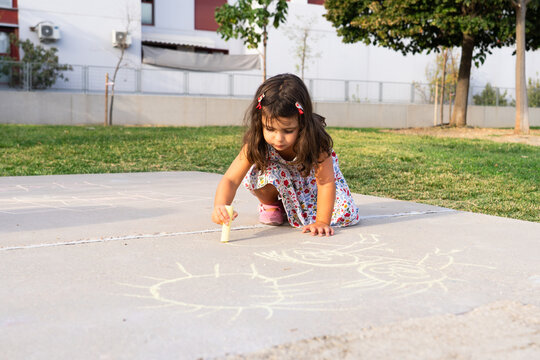 Little girl drawing with chalk on sidewalk outdoors