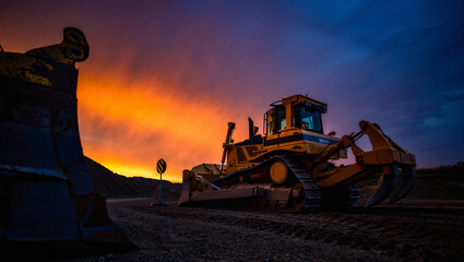 Heavy bulldozer working on a construction site at dramatic sunset with vibrant sky. © Sabbir Digital