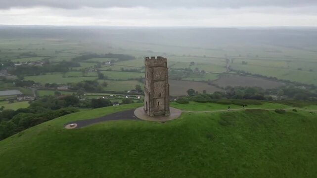 High Altitude Aerial Approach to Glastonbury Tor with St Michaels Tower Against Dramatic Cloudy Sky