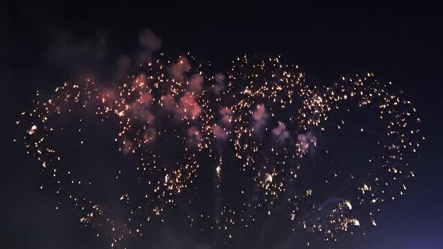 Red heart shaped fireworks explode in dark night sky over city