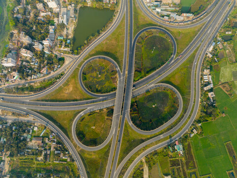 Aerial view of the intersection with elegantly curving ramps and green spaces, a symphony of concrete and nature coexisting harmoniously, Bhanga, Dhaka Division, Bangladesh.
