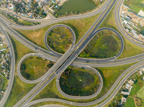 Aerial view of the cloverleaf interchange where concrete ribbons meet verdant patches, a testament to modern infrastructure, Bhanga, Dhaka Division, Bangladesh.