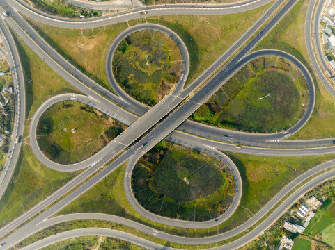 Aerial view of a cloverleaf interchange with roads cutting through green spaces, creating a complex web of infrastructure, Bhanga, Dhaka Division, Bangladesh.
