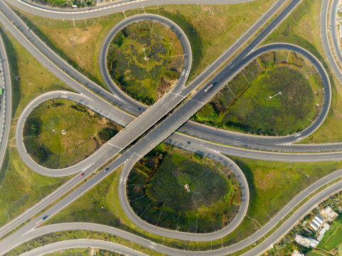 Aerial view of a cloverleaf interchange with roads curving gracefully around patches of green, Bhanga, Dhaka Division, Bangladesh.