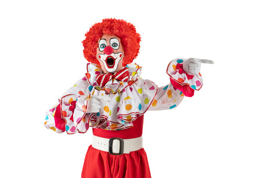 Surprised clown pointing at blank template copy spase for advertising, posters, greetings, invitations. Entertainer as Joker in a suit and wig, with clown whiteface makeup.