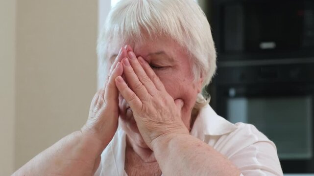 Close up portrait of senior sick woman rubbing her sore nose at home. Sinusitis problem concept