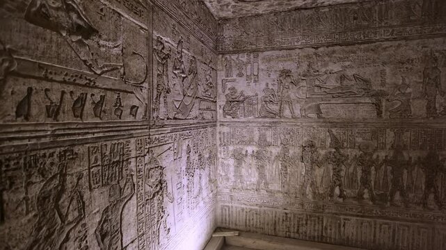 Dendera temple interior sanctuary with illuminated hieroglyphic walls and ritual reliefs in Egypt, ancient sacred chamber with dramatic lighting on carved sandstone surfaces.