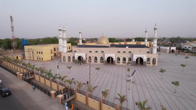 Aerial view of a mosque featuring a golden dome and tall minarets, surrounded by a vast patterned courtyard, Kano, Kano, Nigeria.