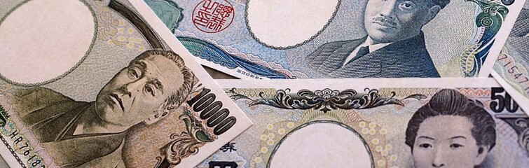 Japanese yen money bills pile on table. Japan banknotes of JPY currency close up. © Larysa