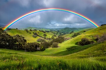Fototapeta premium Rainbow arching over vibrant green hills and valley