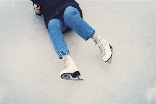 legs and ice skates of a fallen girl on the ice, showing a moment of slip or fall during skating.