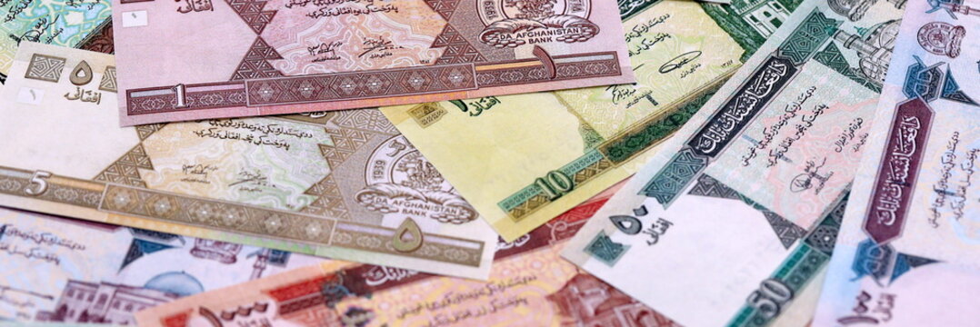 Afghan afghani money bills pile on table. Afghanistan banknotes of AFN currency close up.