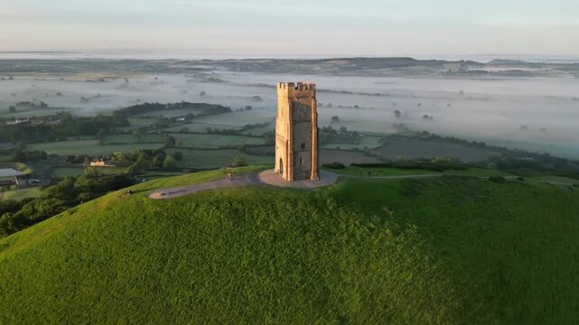 Golden Sunrise Aerial Orbit Around St Michaels Tower Glastonbury Tor with Morning Mist Over Somerset