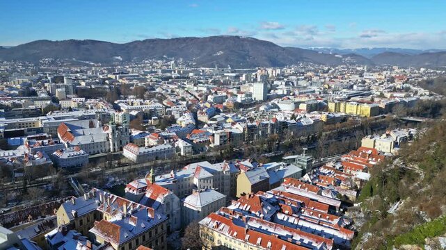 Aerial view of buildings with snow-covered roofs, creating a beautiful contrast against the clear blue sky, Graz, Styria, Austria.
