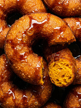 Macro of Peruvian Picarones fried pumpkin donuts with sweet chancaca syrup glaze. Traditional ethnic dessert with golden crunchy and soft dough texture.