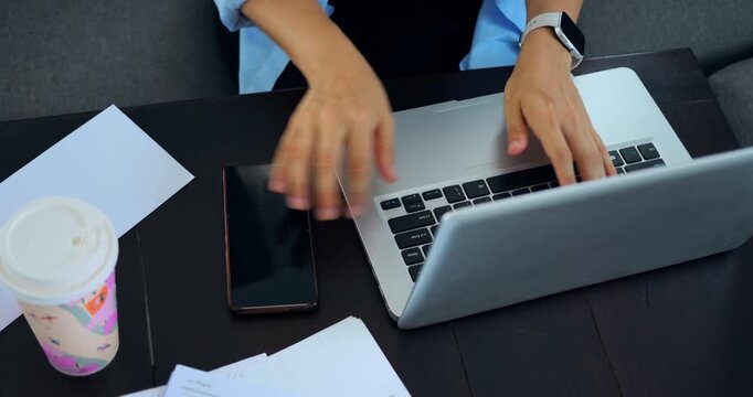 Individual juggling messages with quick research. Person scrolling phone amid papers and coffee on dark table. Someone working efficiently on multiple tasks with casual cafe atmosphere presence