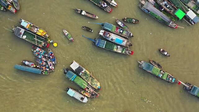 Drone shot of traditional boats trading goods at Cai Rang floating market on the river in Vietnam. Colorful vessels filled with fresh produce create a vibrant scene from above.
