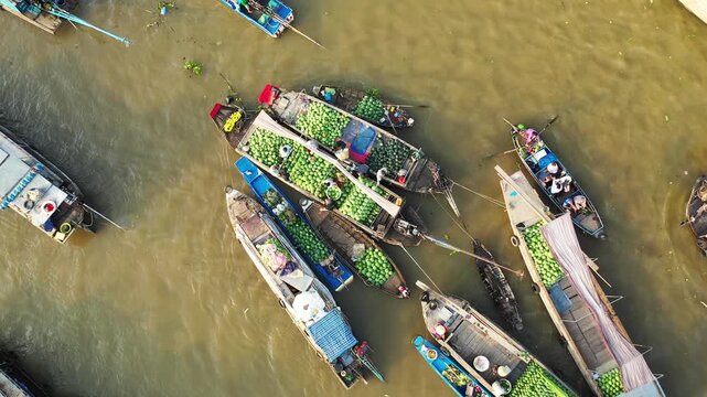 Aerial view of traditional boats loaded with produce at the Cai Rang floating market in Vietnam. Bustling river scene with vibrant fruits and local commerce.