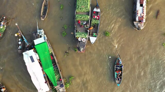 Aerial view of boats loaded with produce at the Cai Rang floating market on a river in Vietnam. Traditional wooden boats and fresh fruits are visible on the water.