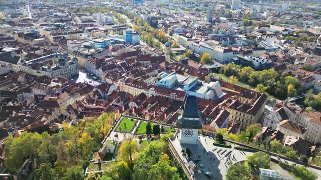 Aerial view of the Grazer Uhrturm clock tower standing tall amidst the vibrant cityscape and lush greenery, a historical landmark, Graz, Styria, Austria.