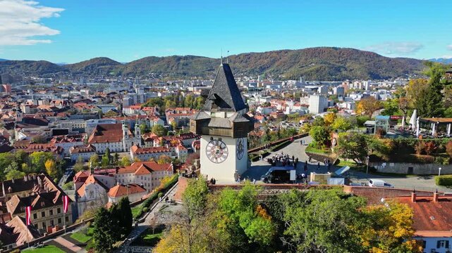 Aerial view of the Grazer Uhrturm clock tower standing tall amidst a vibrant cityscape with red rooftops, Graz, Styria, Austria.