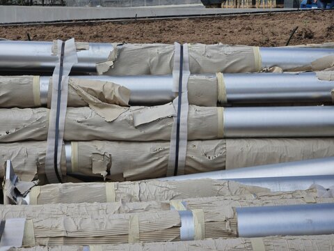 A pile of pipes with tape on them. The tape is yellow and black. The pipes are stacked on top of each other
