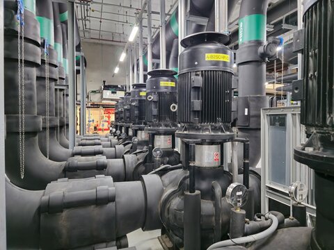 A series of black pipes with a yellow label on the top. The pipes are connected to a large machine