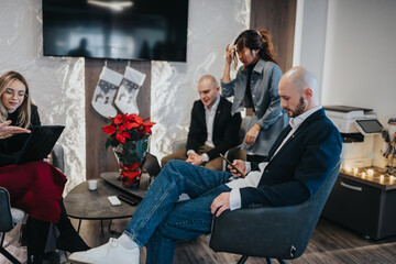 Naklejka premium A professional group sits in a modern office lounge, ready for a meeting. Casual business scene with colleagues waiting beside a festive desk.