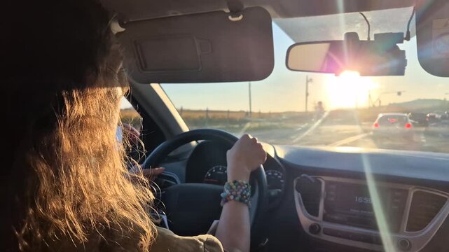 Driving sunset highway, young woman traveling during golden hour traffic congestion on a beautiful summer road trip.