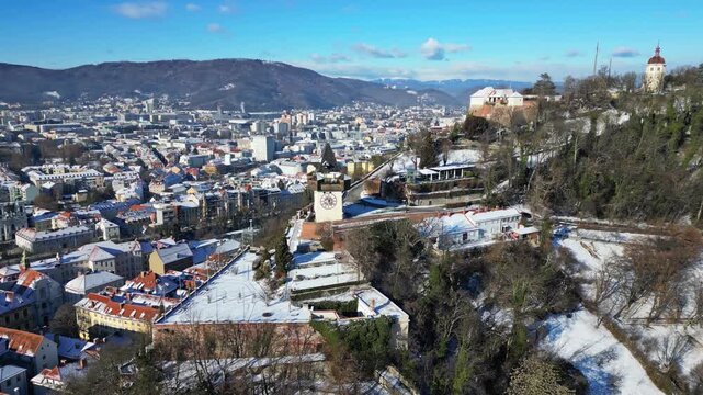 Aerial view of the Grazer Uhrturm, its clock tower standing prominently over the snow dusted city, Graz, Styria, Austria.