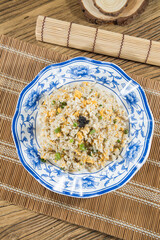 A blue rimmed plate holds fluffy fried rice studded with egg and scallion, finished with a small mound of roe. Shot overhead on bamboo mats for a homely, comforting look.