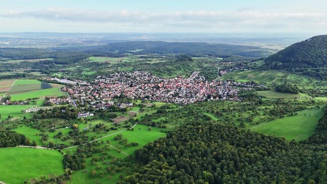 Aerial view of Neuffen town nestled amid verdant fields and forests, a patchwork of green and brown, creating a captivating contrast, Erkenbrechtsweiler, Baden-Wurttemberg, Germany.