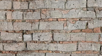 Close-up of an old brick wall with rough cement mortar and uneven texture. Weathered masonry surface with natural tones, ideal for construction, architecture, and urban backgrounds.