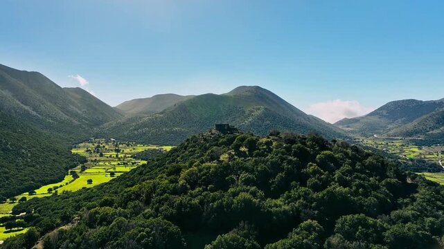 Aerial view of lush green fields and mountains contrasting with the clear blue sky, creating a vibrant landscape, Askifou, Chania, Greece.
