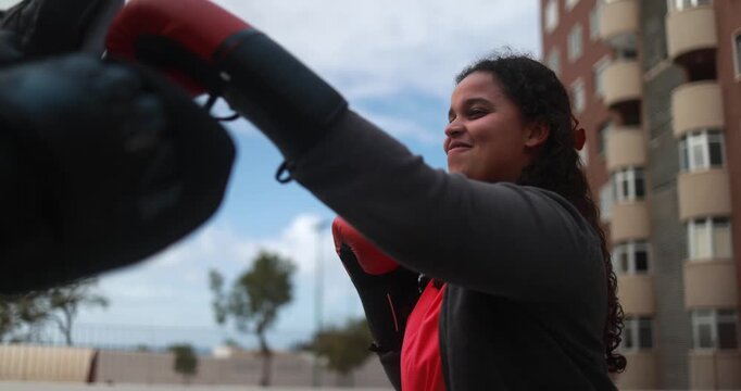 Curvy african american girl having fun during boxing exercise with personal trainer outdoor - Fitness coach, sport and diet concept