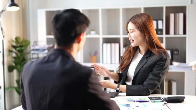 Professional human resources manager interviewing a male applicant for a vacant position in the office. Two young Asian business people discussing a project during a corporate meeting