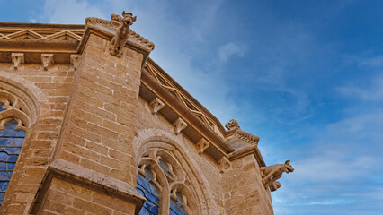 Gothic stone church facade with whimsical gargoyles and stained glass. For travel, architecture, religion and European heritage design concepts. © Yuliya