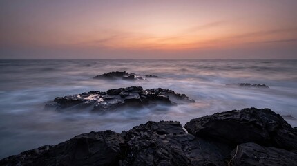 Sunset over the ocean and beach with waves and rocks under a colorful sky