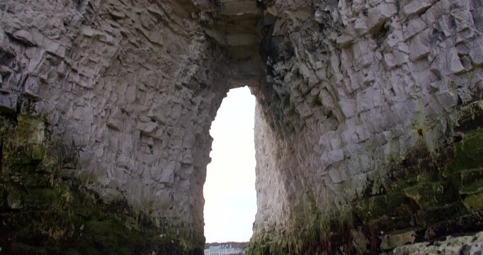 Mid shot Tilting up looking though the Kingsgate Arch chalk stack with Kingsgate bay in background.