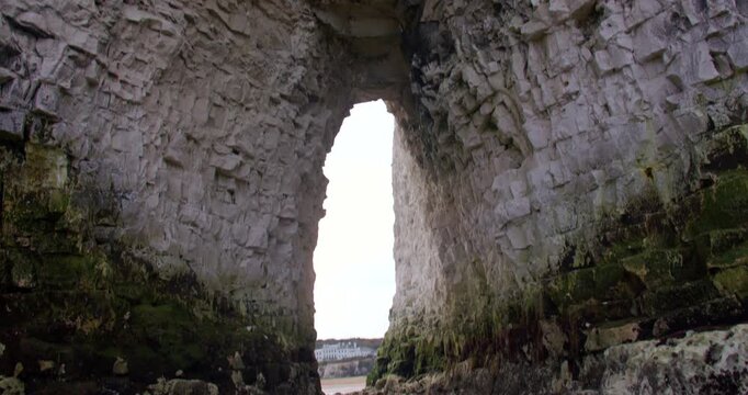 Mid shot Tilting down looking though the Kingsgate Arch chalk stack with Kingsgate bay in background.