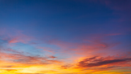 Obraz premium Beautiful panoramic sunset sky with colorful clouds in blue and golden orange hues,A stunning wide-angle shot of a vibrant sunset sky featuring a dramatic blend of fiery orange, soft pink, 