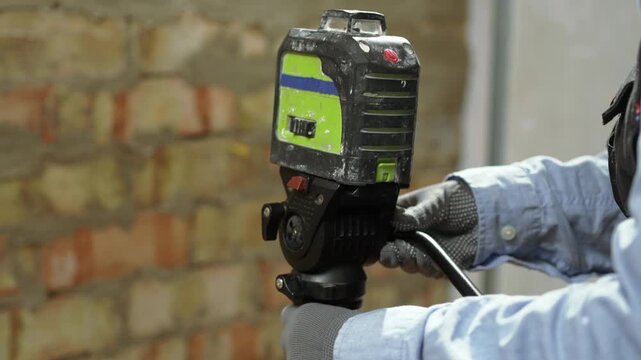 Professional laser level tool on tripod checking vertical alignment and geometry of brick wall