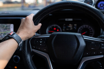 Close-up of Man Hand on Steering Wheel Driving Car with GPS Navigation and Smart Watch,A close-up, first-person perspective of a man's hand holding a leather steering wheel while driving.