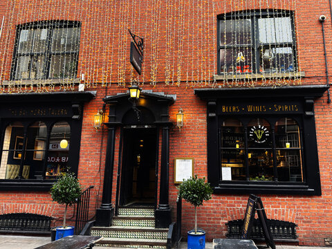 Beers Wines Spirits The Bay Horse Tavern pub facade in Manchester, UK with warm lights and festive holiday decor
