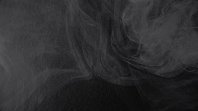 Gray Vapor on Dark Backdrop. Vapor emerging from shadows, forming transient shapes.