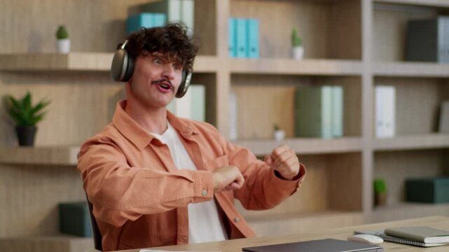 Caucasian business man funny dancing moving singing song wearing headphones humorous businessman ridiculous male guy worker listening music dance move with hands sing fooling around at table in office