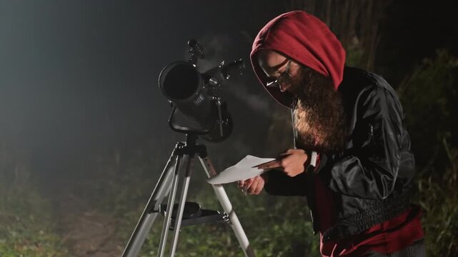 Bearded white man adjusting telescope, closeup in dark field, checking tablet and focus, red hooded jacket, tripodmounted scope, misty atmosphere, methodical calibration, amateur scientist observing