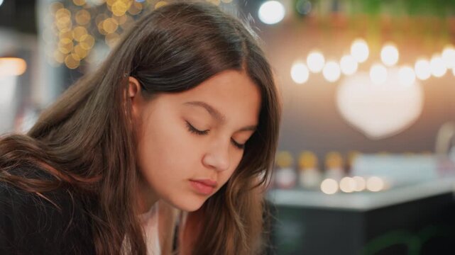 student girl studying in cozy cafe with warm bokeh heart lights, evening scene with soft glow and coffee aroma, pen and notebook in hand, journaling and sketching while focused, relaxed determined