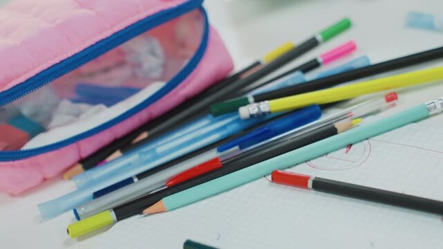 pink pencil case with scattered pencils and pens, closeup overhead of notebook page, pastel eraser shavings and colorful markers, graphite tips and sharpener visible, messy student study prep mood,