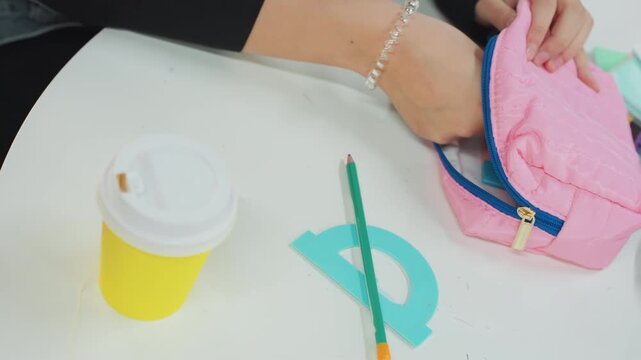 Pencil case arrangement. Student organizing pastel stationery items. Morning scene with study essentials and colorful supplies. Youthful student preparing desk with pink pouch and vibrant tools